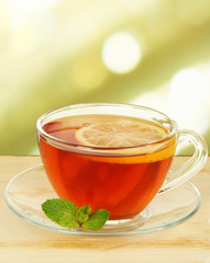 Cup of tea with lemon on table on light background