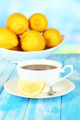 Cup of tea with lemon on table on blue background