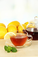Cup of tea with lemon on table on light background
