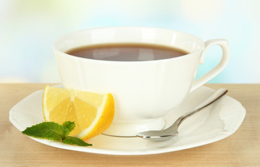 Cup of tea with lemon on table on light background