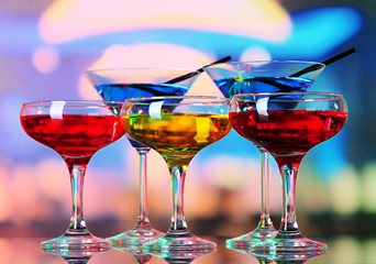 Glasses of cocktails on bright background