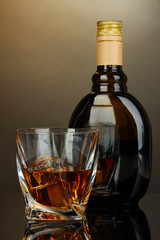 Glass of liquor with bottle, on dark background