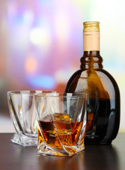 Glass of liquor with bottle, on dark background