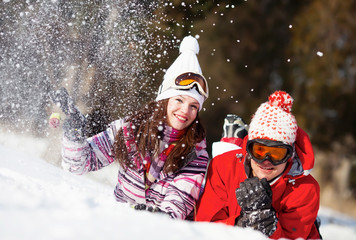 Girl and boy laying on the snow in park