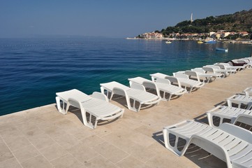 Empty sunbeds in beach of Podgora in morning. Croatia
