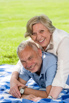 Laughing senior couple on picnic blanket