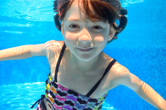 Happy child swims underwater in pool, girl having fun