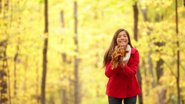 Happy girl playing in autumn leaves, fall forest
