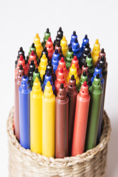 colored pens in a box on a light background