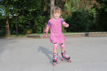 young happy child girl riding roller blades outdoors