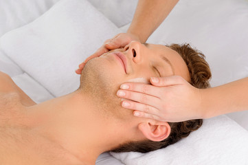 Fototapeta na wymiar Facial massage. Top view of relaxed young men lying on the massa