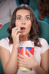 Obraz premium Women at the cinema. Beautiful young women eating popcorn while