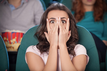 Fototapeta premium Watching horror movie. Terrified young women covering her face