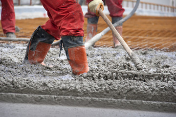 Group of construction workers spreading freshly poured concrete