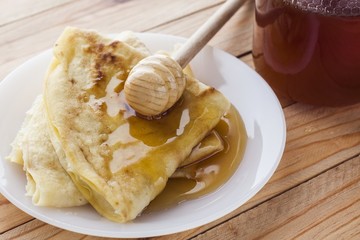 Stack of pancakes with honey on wood table