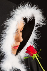 Fototapeta premium Portrait of sad woman in black cape and rose artistic conversion