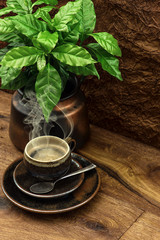 black coffee and fresh plant on wooden table