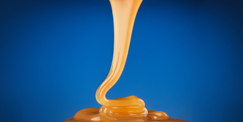 honey, syrup or caramel runs down on a blue background