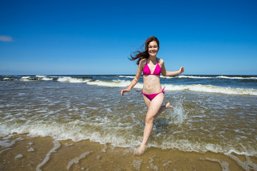 Teenage girl running, jumping on beach