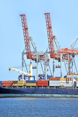 Fototapeta premium Container stack and ship under crane bridge