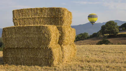 An air balloon appearing behind some bales of straw