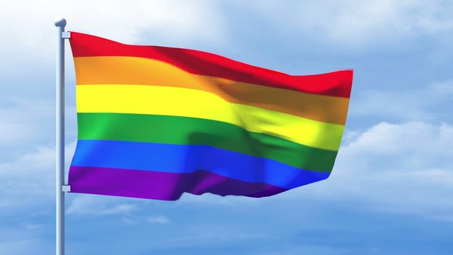 LGBT flag waving over a cloudy blue sky