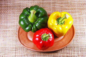green yellow and red sweet pepper in clay dish on Straw mat
