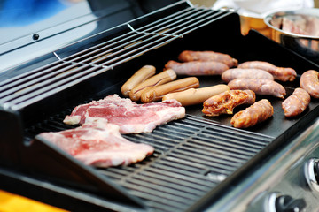 sausages and steaks cooking on a barbecue grill