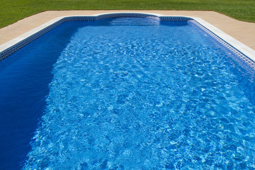 View of a big luxurious swimming pool with grass.