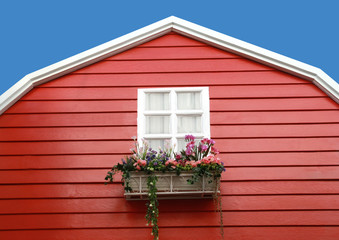 white window with flower on red barn