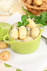 Tender young potatoes with sour cream and herbs in pan