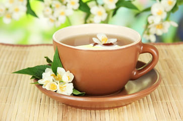 Cup of tea with jasmine, on bamboo mat, on bright background