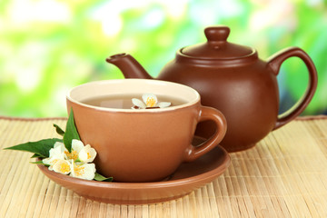 Cup of tea with jasmine, on bamboo mat, on bright background