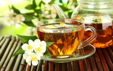 Cup of tea with jasmine, on bamboo mat, close-up