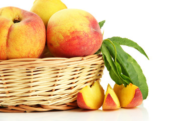 Ripe sweet peaches with leaves in basket, isolated on white