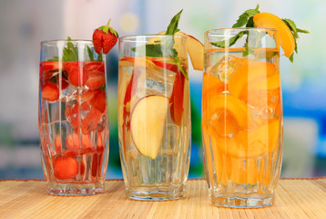 Glasses of fruit drinks with ice cubes on table in cafe