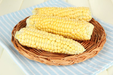 Fresh corn on wicker mat, on wooden background