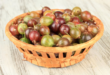 Fresh gooseberries in wicker basket on table close-up