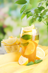 Iced tea with lemon and mint on table, outdoors