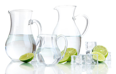 Glass pitchers of water with ice and lime isolated on white