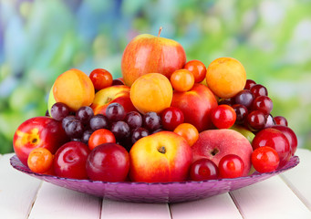 Assortment of juicy fruits on wooden table, on bright