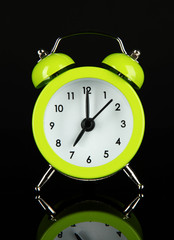 Green alarm clock on dark grey background