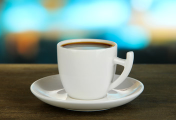 Cup of coffee on wooden table on bright background