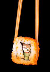 delicious sushi and chopsticks on black background