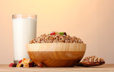 Boiled buckwheat in a wooden bowl with a glass of milk