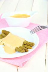 Asparagus on plate, on wooden background