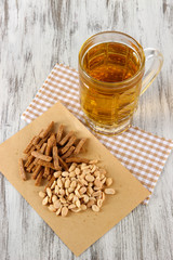Beer in glass crunches, and nuts on napkin on wooden table