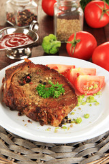 Piece of fried meat on plate on wooden table close-up
