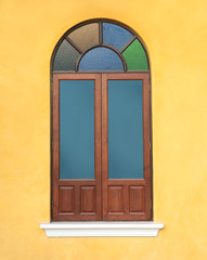 wood window with colorful glass on yellow wall