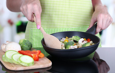 Hands cooking vegetable ragout in pan in kitchen